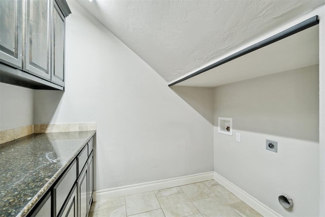 washroom featuring cabinet space, hookup for an electric dryer, baseboards, hookup for a washing machine, and a textured ceiling