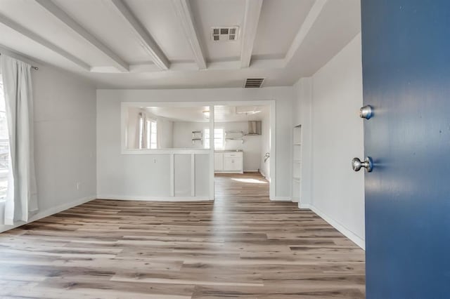 unfurnished living room with wood finished floors, baseboards, and beamed ceiling