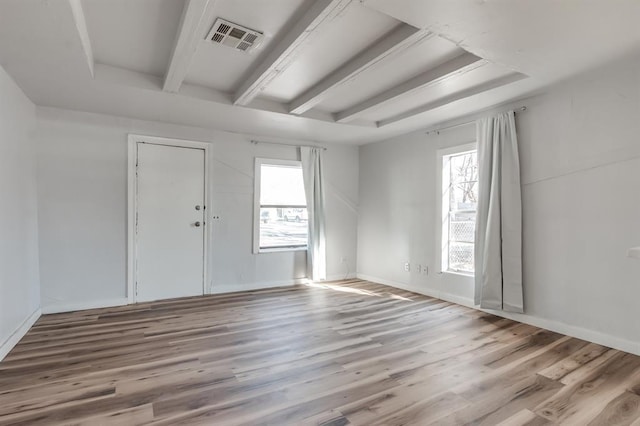 empty room featuring wood finished floors, beam ceiling, and baseboards