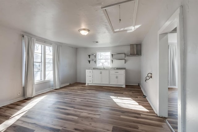 kitchen with wall chimney exhaust hood, open shelves, white cabinets, wood finished floors, and baseboards