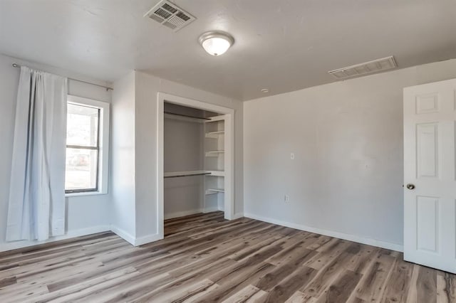 unfurnished bedroom featuring wood finished floors, a closet, and baseboards