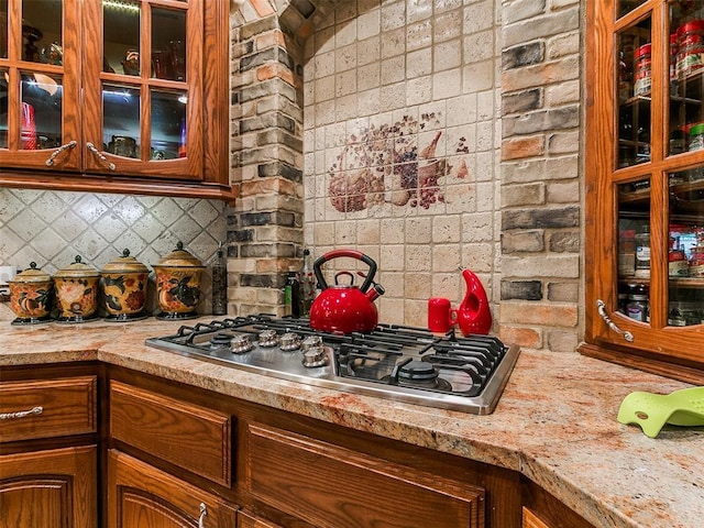 8501 S Council Rd, Oklahoma City, OK 73169 - kitchen featuring stainless steel gas cooktop, decorative backsplash, glass insert cabinets, and brown cabinets