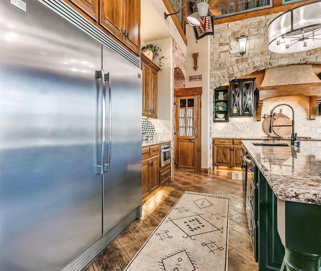 5400 N Piedmont Rd Unit A, Piedmont, OK 73078 - kitchen with built in fridge, a sink, tasteful backsplash, brown cabinets, and light stone countertops