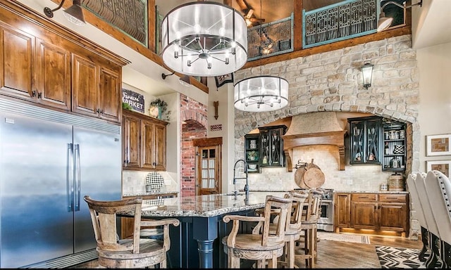 5400 N Piedmont Rd Unit A, Piedmont, OK 73078 - kitchen with premium appliances, a towering ceiling, light stone countertops, tasteful backsplash, and a center island with sink