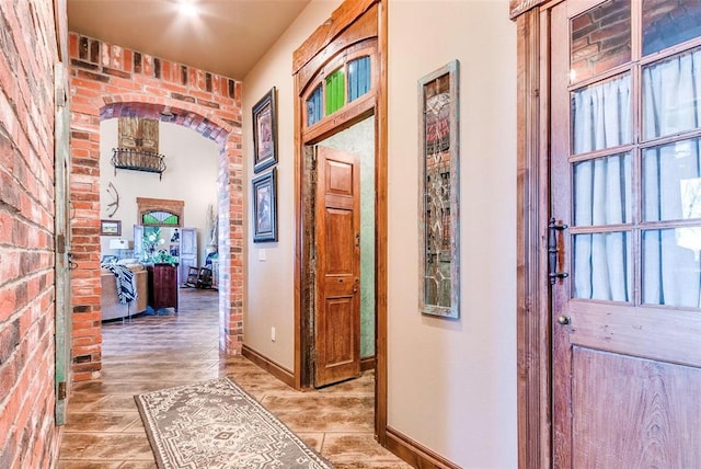 5400 N Piedmont Rd Unit A, Piedmont, OK 73078 - hallway featuring light wood-style floors, arched walkways, baseboards, and brick wall