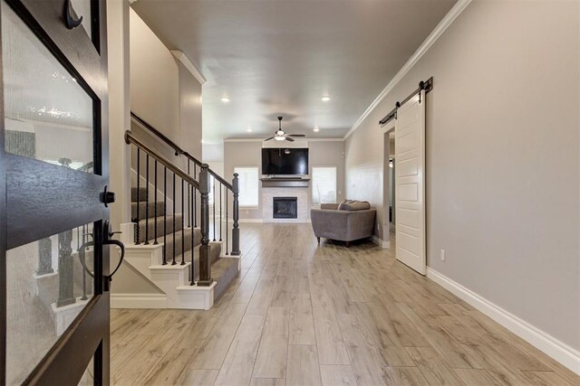 3024 Drake Crest Dr, Edmond, OK 73034 - living area featuring a stone fireplace, ceiling fan, ornamental molding, a barn door, and stairs