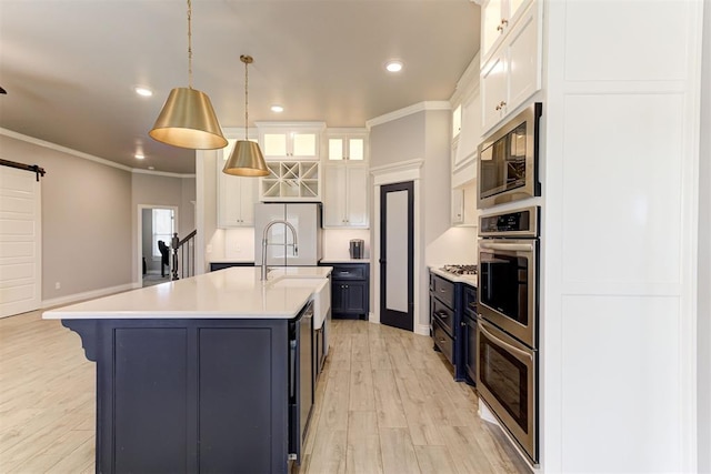 3024 Drake Crest Dr, Edmond, OK 73034 - kitchen featuring stainless steel appliances, a barn door, light countertops, light wood-style flooring, and crown molding