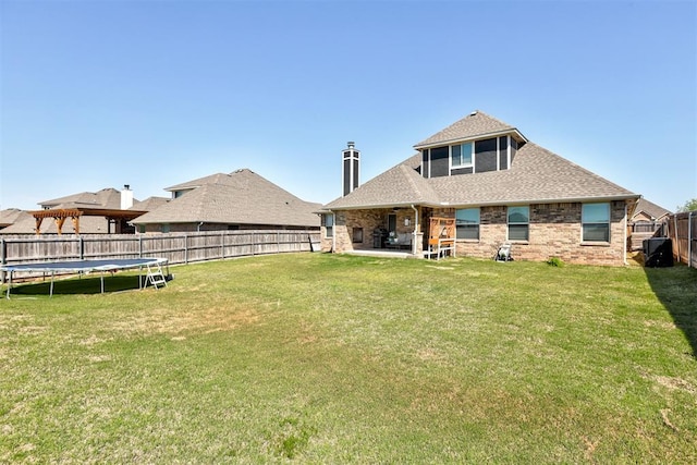 3024 Drake Crest Dr, Edmond, OK 73034 - rear view of house with roof with shingles, a trampoline, a patio area, and brick siding