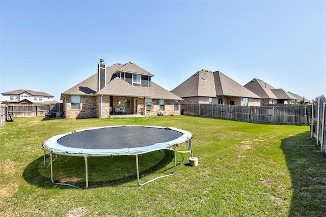 3024 Drake Crest Dr, Edmond, OK 73034 - back of house with a trampoline, a chimney, brick siding, and roof with shingles