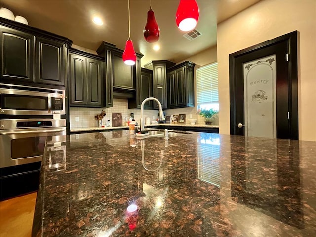 16175 Silver Run Dr, Choctaw, OK 73020 - kitchen featuring stainless steel appliances, a sink, backsplash, decorative light fixtures, and dark stone counters