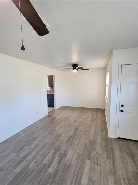 2421 N Prospect Ave, Oklahoma City, OK 73111 - unfurnished living room featuring ceiling fan, light wood-style flooring, and baseboards