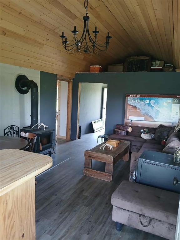 218 N 4150th Rd, Antlers, OK 74523 - living room with a wood stove, vaulted ceiling, wood ceiling, wood finished floors, and a chandelier