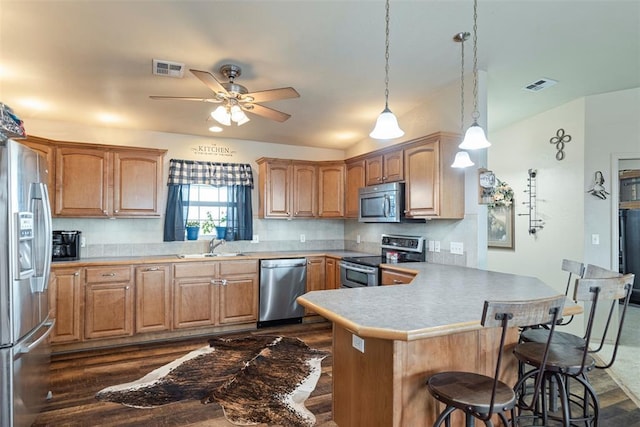22950 E 1130th Rd, Bessie, OK 73622 - kitchen featuring stainless steel appliances, a peninsula, a breakfast bar, a ceiling fan, and dark wood-style floors