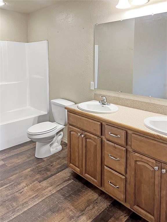 22950 E 1130th Rd, Bessie, OK 73622 - full bathroom featuring double vanity, wood finished floors, and shower / washtub combination