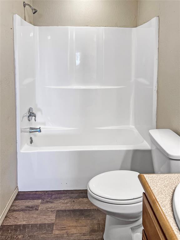 22950 E 1130th Rd, Bessie, OK 73622 - bathroom with vanity, wood finished floors, shower / bath combination, and a textured wall