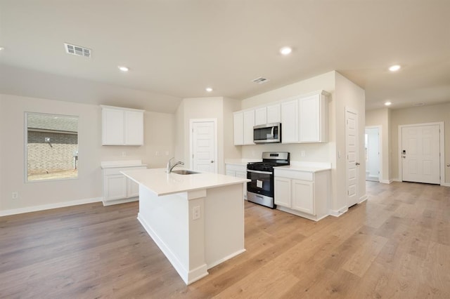 10324 NW 28th St, Yukon, OK 73099 - kitchen featuring appliances with stainless steel finishes, a sink, a center island with sink, white cabinets, and light countertops