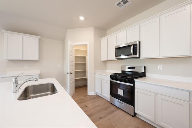 10324 NW 28th St, Yukon, OK 73099 - kitchen with appliances with stainless steel finishes, a sink, light countertops, white cabinets, and recessed lighting