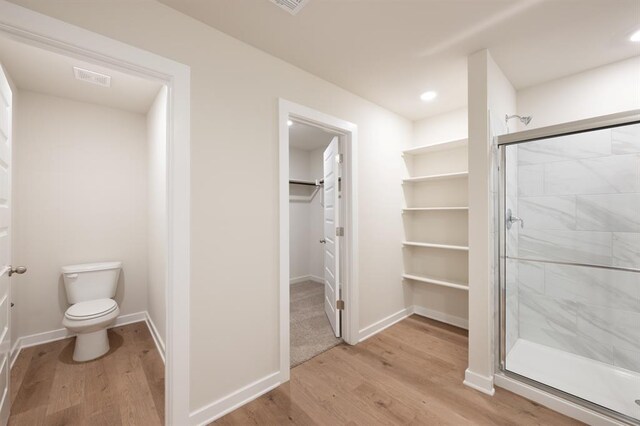 10324 NW 28th St, Yukon, OK 73099 - full bathroom with wood finished floors, a stall shower, toilet, a walk in closet, and recessed lighting