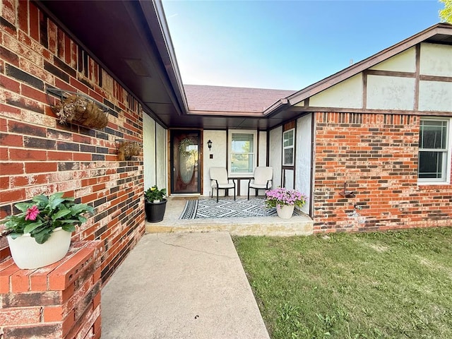 view of exterior entry with brick siding and covered porch