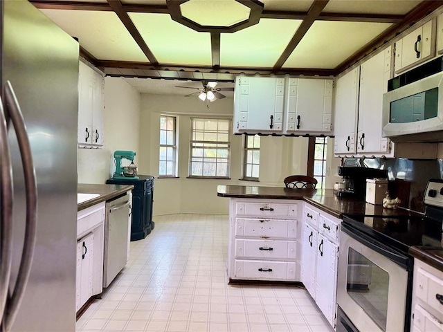 kitchen with appliances with stainless steel finishes, ceiling fan, dark countertops, a peninsula, and baseboards