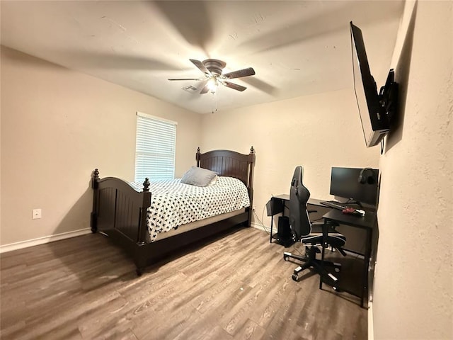 bedroom featuring wood finished floors, baseboards, an office area, and ceiling fan