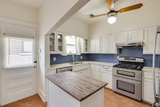 2534 NW 19th St, Oklahoma City, OK 73107 - kitchen with range with two ovens, a sink, under cabinet range hood, tasteful backsplash, and light tile patterned floors