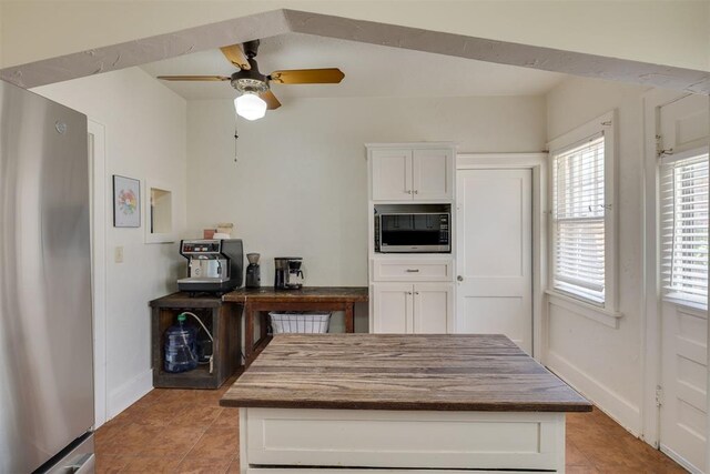 2534 NW 19th St, Oklahoma City, OK 73107 - kitchen featuring stainless steel appliances, light tile patterned flooring, a ceiling fan, white cabinets, and baseboards