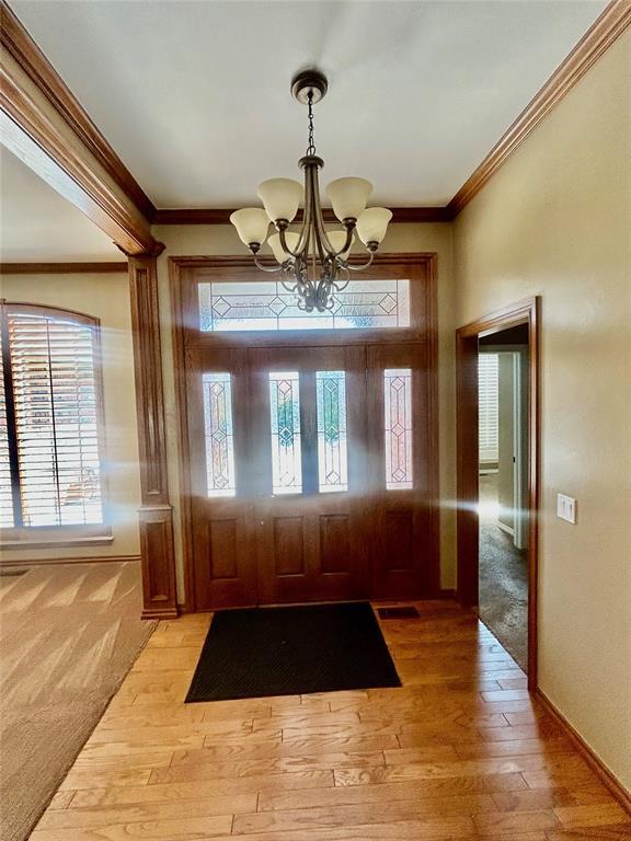 9817 Horseshoe Rd, Oklahoma City, OK 73162 - foyer entrance featuring a chandelier, ornamental molding, light wood-style flooring, and baseboards