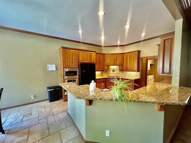 9817 Horseshoe Rd, Oklahoma City, OK 73162 - kitchen with appliances with stainless steel finishes, brown cabinets, a kitchen bar, light stone countertops, and recessed lighting