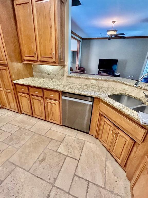 9817 Horseshoe Rd, Oklahoma City, OK 73162 - kitchen featuring dishwasher, stone tile flooring, a sink, tasteful backsplash, and brown cabinetry