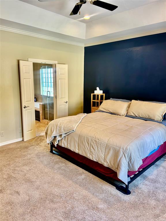 9817 Horseshoe Rd, Oklahoma City, OK 73162 - carpeted bedroom featuring baseboards, ornamental molding, a ceiling fan, and a raised ceiling