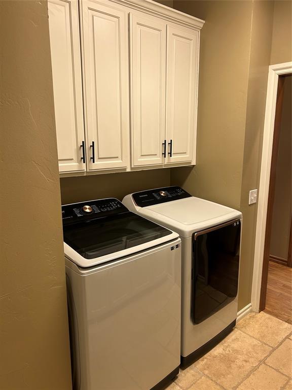 9817 Horseshoe Rd, Oklahoma City, OK 73162 - laundry room with separate washer and dryer, cabinet space, light stone finish flooring, and baseboards