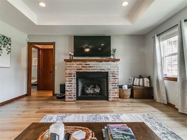 1015 N 3rd Ave, Stroud, OK 74079 - living area with a tray ceiling, wood finished floors, a brick fireplace, baseboards, and recessed lighting