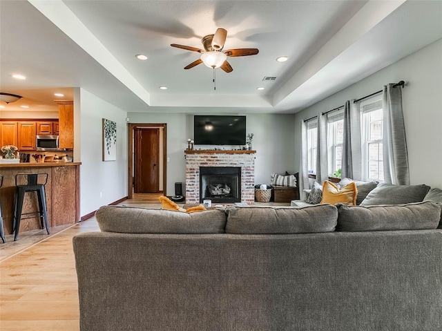 1015 N 3rd Ave, Stroud, OK 74079 - living room with a raised ceiling, light wood-style floors, ceiling fan, a fireplace, and recessed lighting