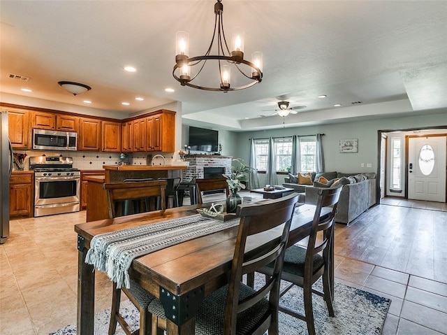 1015 N 3rd Ave, Stroud, OK 74079 - dining space featuring a raised ceiling, a ceiling fan, a chandelier, light tile patterned flooring, and recessed lighting
