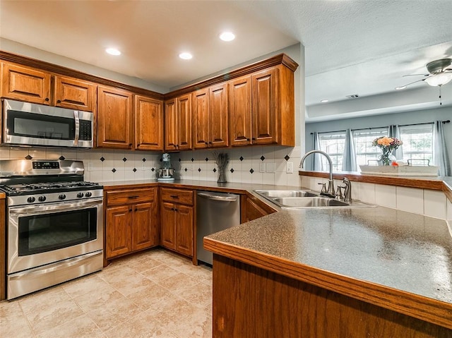 1015 N 3rd Ave, Stroud, OK 74079 - kitchen with stainless steel appliances, a sink, brown cabinetry, a peninsula, and decorative backsplash