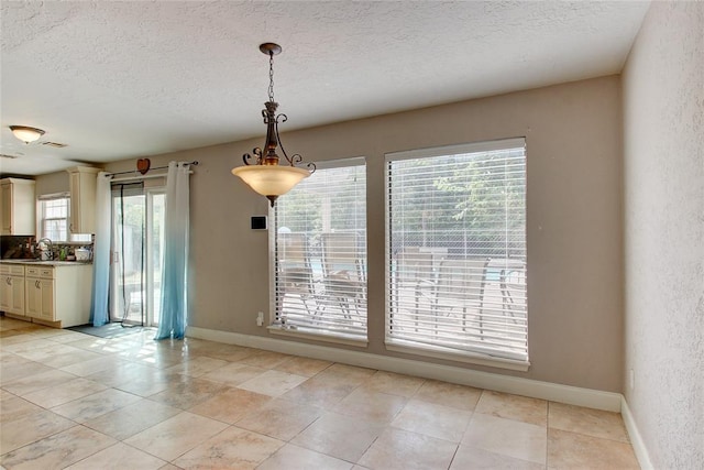 913 NE Dove Ln, Lawton, OK 73507 - unfurnished dining area with baseboards, a textured ceiling, a textured wall, and light tile patterned floors