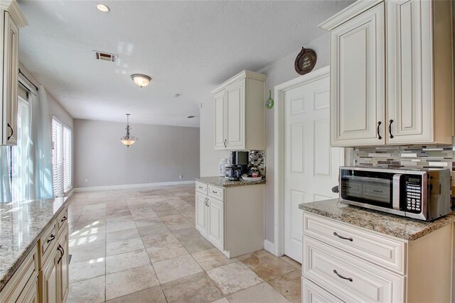 913 NE Dove Ln, Lawton, OK 73507 - kitchen with stainless steel microwave, decorative backsplash, baseboards, and light stone countertops