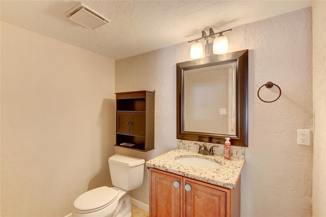 913 NE Dove Ln, Lawton, OK 73507 - bathroom featuring toilet, a textured wall, vanity, a textured ceiling, and baseboards