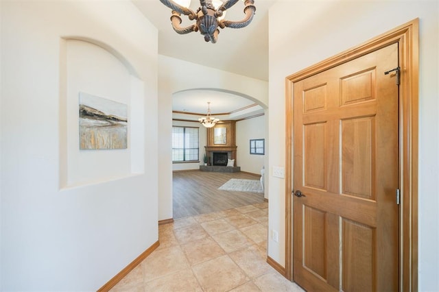10681 NW 107th St, Yukon, OK 73099 - hallway featuring a chandelier, arched walkways, and baseboards