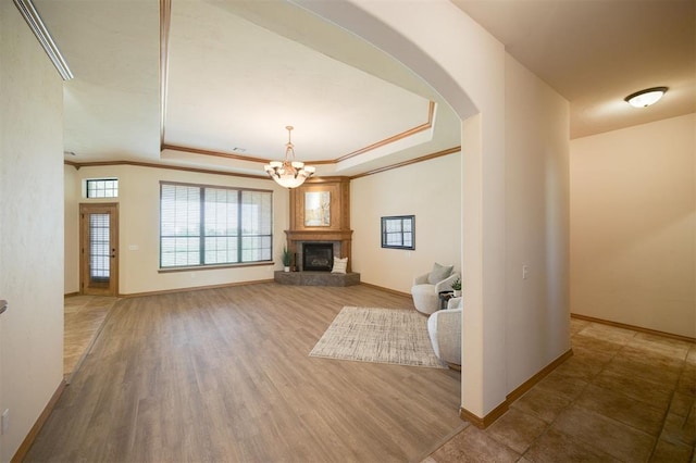 10681 NW 107th St, Yukon, OK 73099 - unfurnished living room featuring a raised ceiling, arched walkways, baseboards, crown molding, and a glass covered fireplace
