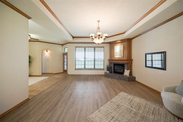 10681 NW 107th St, Yukon, OK 73099 - unfurnished living room with a tray ceiling, a chandelier, wood finished floors, ornamental molding, and baseboards