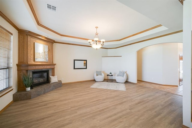 10681 NW 107th St, Yukon, OK 73099 - unfurnished living room featuring a tray ceiling, a chandelier, crown molding, a large fireplace, and arched walkways