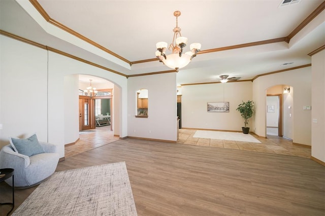 10681 NW 107th St, Yukon, OK 73099 - unfurnished living room featuring arched walkways, a chandelier, a tray ceiling, and crown molding