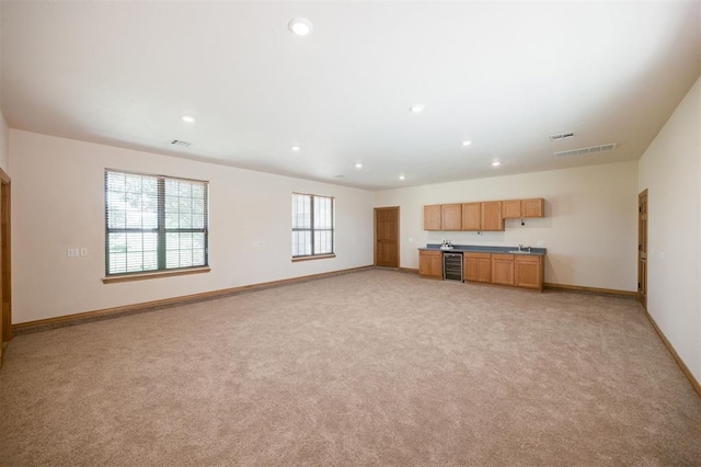 10681 NW 107th St, Yukon, OK 73099 - unfurnished living room featuring beverage cooler, light colored carpet, baseboards, recessed lighting, and a sink