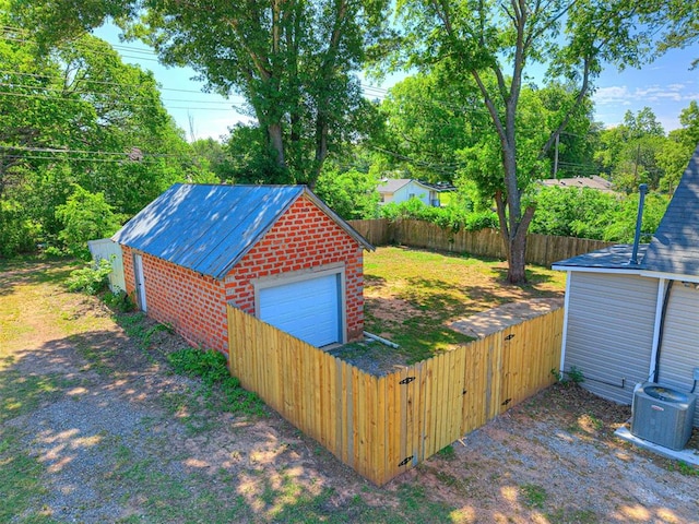 908 N Barta Ave, Prague, OK 74864 - view of outbuilding featuring an outbuilding, a fenced backyard, driveway, central AC, and view of scattered trees