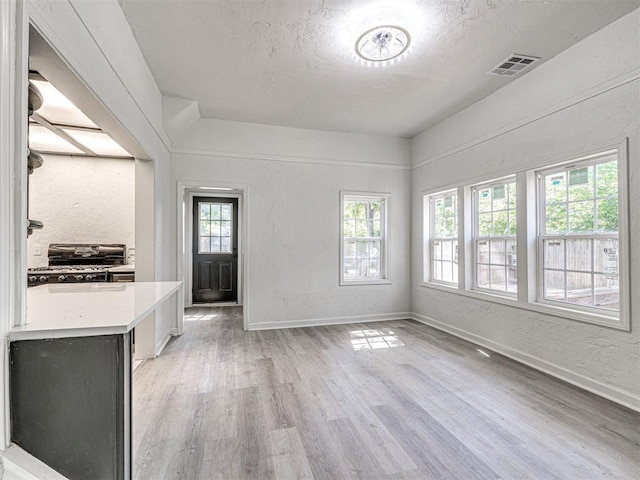 908 N Barta Ave, Prague, OK 74864 - unfurnished dining area featuring light wood-style flooring, a textured wall, baseboards, and a textured ceiling