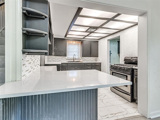 908 N Barta Ave, Prague, OK 74864 - kitchen featuring stainless steel gas stove, a sink, light marble finish flooring, a peninsula, and decorative backsplash
