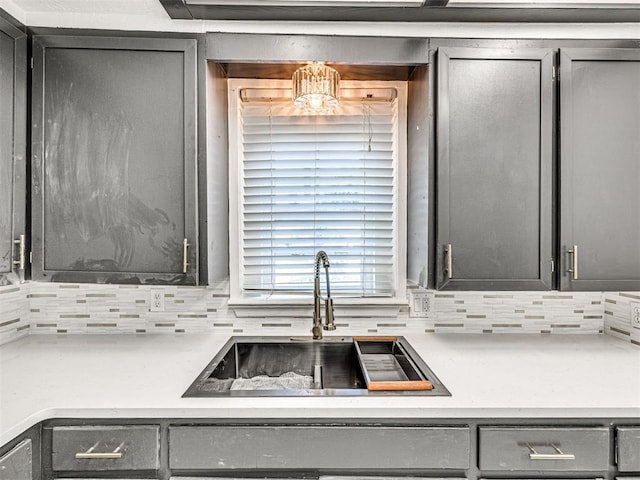 908 N Barta Ave, Prague, OK 74864 - kitchen with gray cabinets, a sink, decorative backsplash, and a chandelier