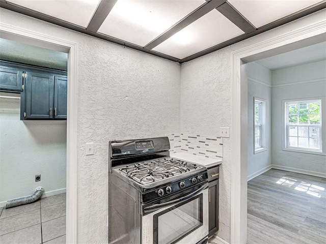 908 N Barta Ave, Prague, OK 74864 - kitchen with gas range, baseboards, blue cabinetry, a textured wall, and light wood-type flooring